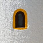 kleines gelb umrandetes Fenster in weisser Wand